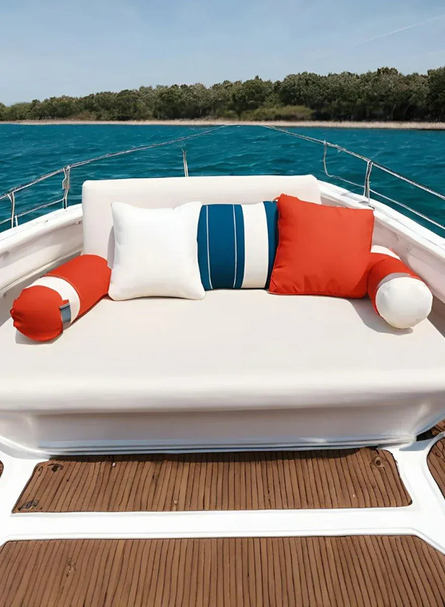 White bow sun pad cushion with bolsters and throw pillows on a boat on a lake