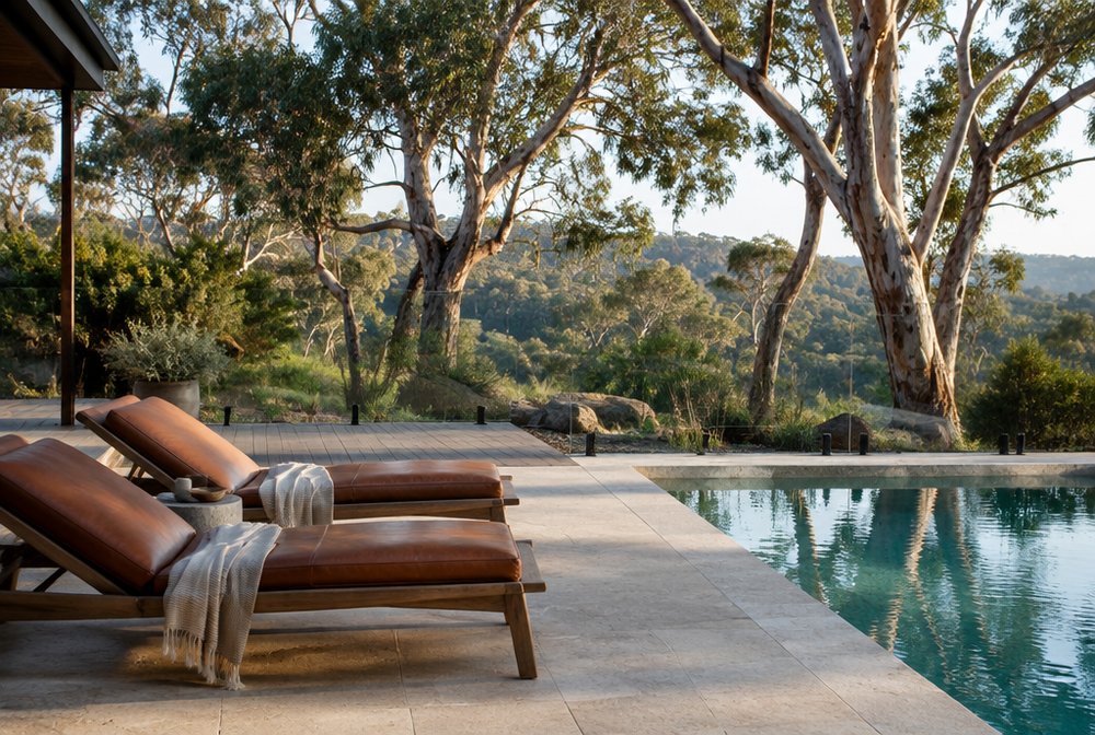 An Australian backyard with lounge chairs topped with cognac leather cushions beside a pool and gum trees