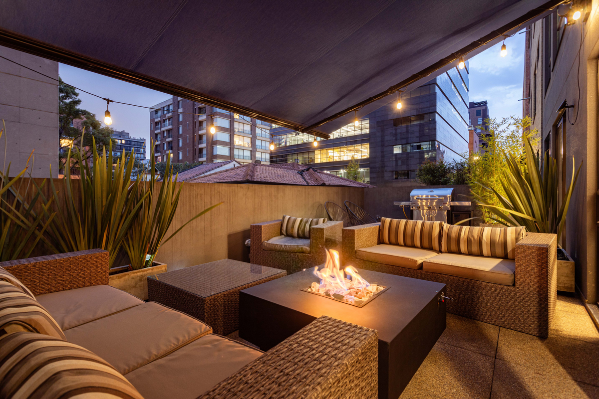Covered outdoor terrace with wicker lounges and custom beige and striped outdoor cushions